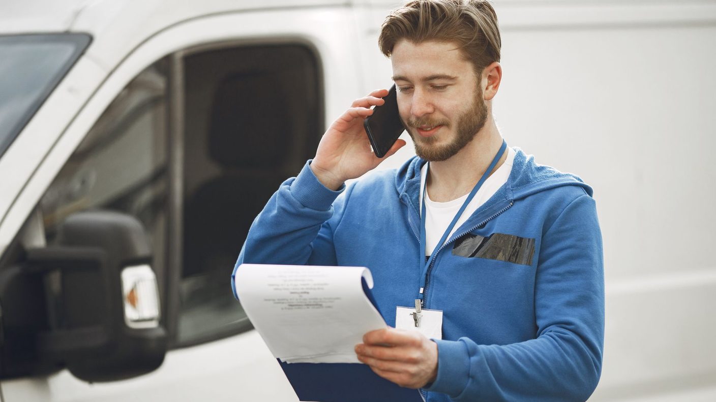 Handwerker mit Transporter nimmt am Telefon eine Kundenanfrage entgegen, Sinnbild für eine Website, die rund um die Uhr Anfragen bringt
