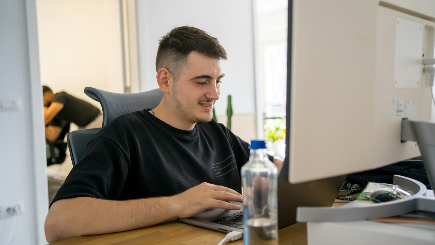 Mann sieht zufrieden am Laptop eine neue Anfrage, die über seine gut gebaute Website hereingekommen ist