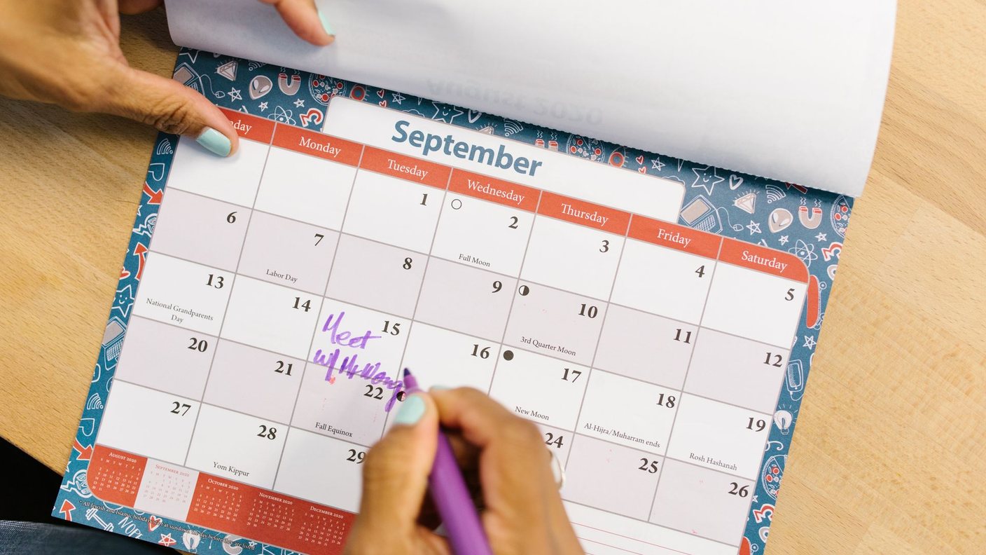 Hand trägt einen Termin in einen Wandkalender ein, Sinnbild für die zeitliche Planung eines Website-Projekts